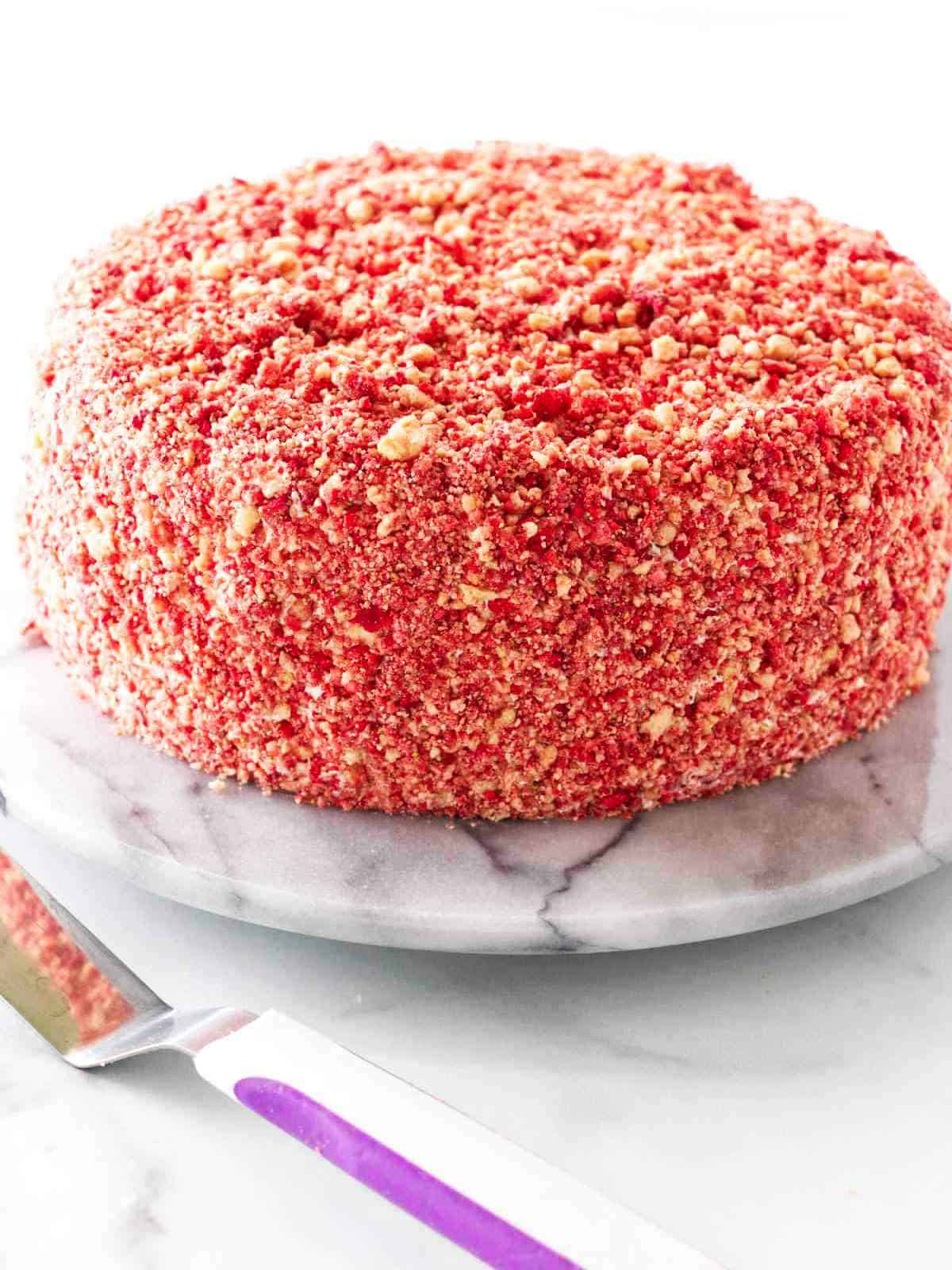 Cake with a strawberry crunch crumble on sides and top.