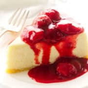 perfect slice of no water bath cheesecake with strawberry sauce on top.